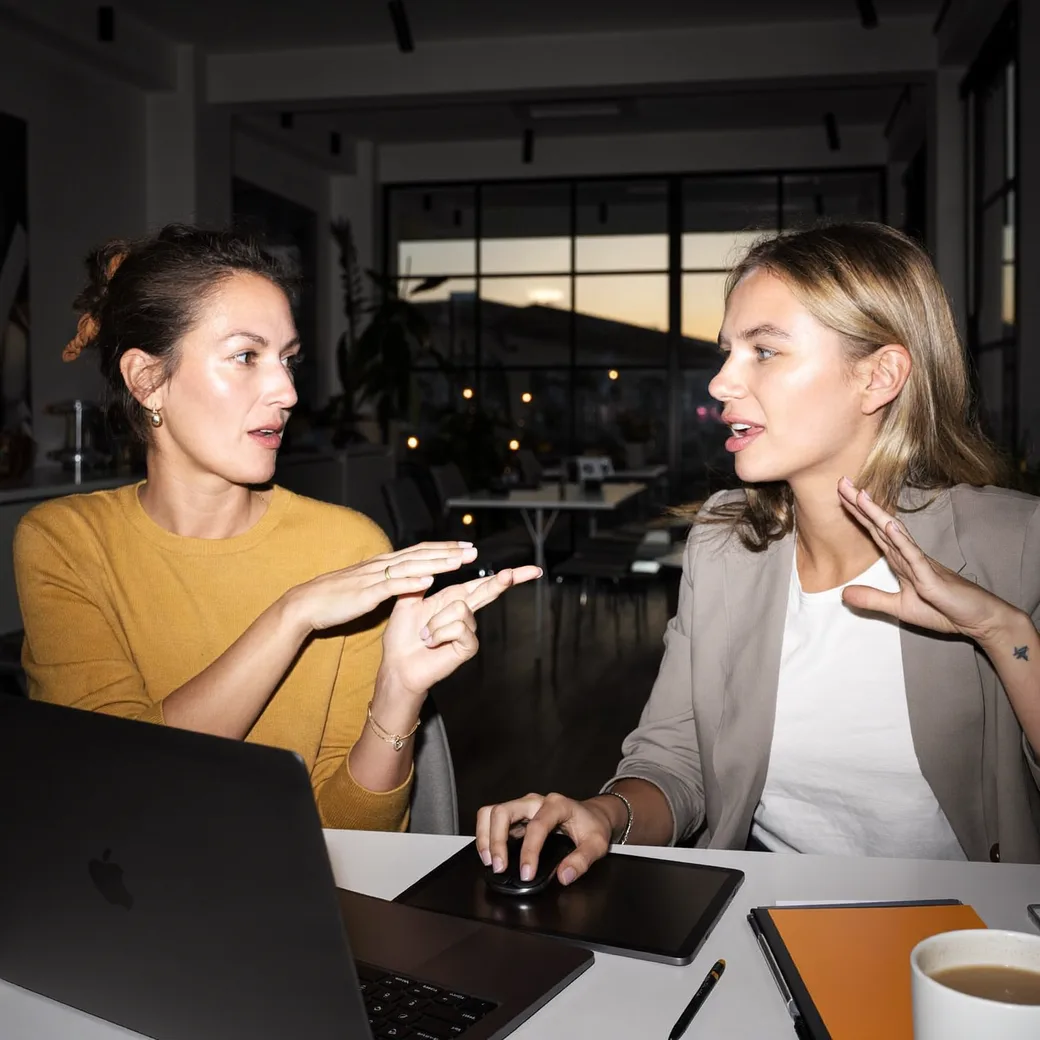 Dwie kobiety rozmawiają przy laptopie w biurze